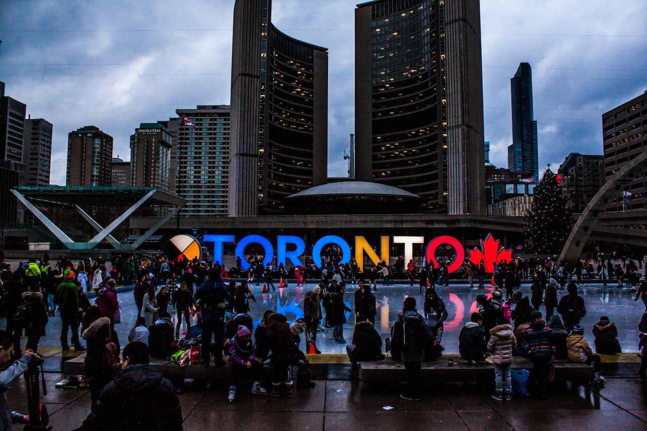 People in front of Toronto colorful sign at dusk