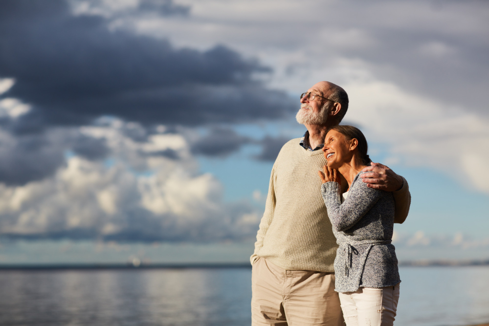 An elderly couple standing near a lake