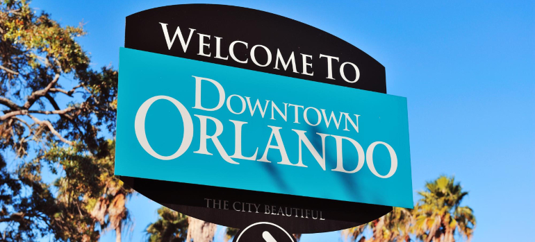A black and blue sign with a tree in the background saying Welcome to Downtown Orlando, The City Beautiful