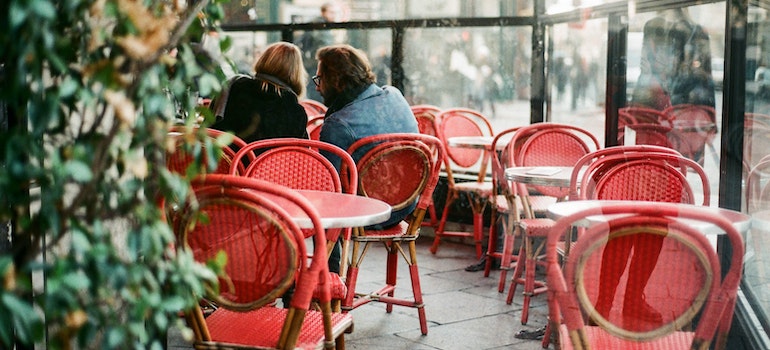 A couple in a caffe in Paris with red chairs