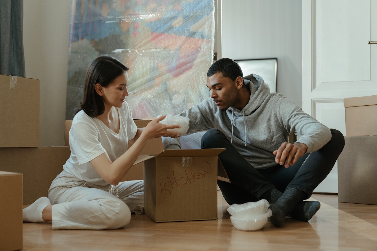 A man and a woman sitting on the floor, unpacking after moving fragile items