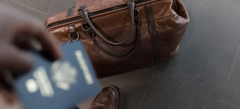 A man standing next to a travel bag and holding a passport
