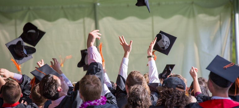 Students throwing their graduation caps in a university before moving from Arizona to Washington