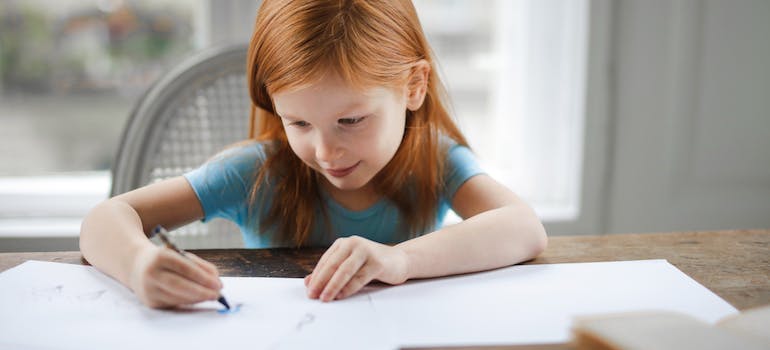 small girl drawing on a paper in the living room