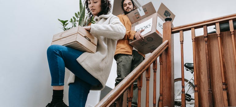 a couple carrying boxes, since they know what how to do it once they read an article on Moving Your Home Office