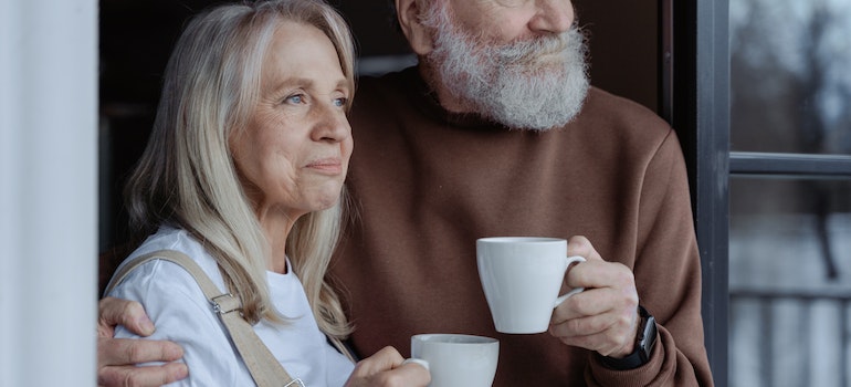 an elderly couple holding cups of coffee