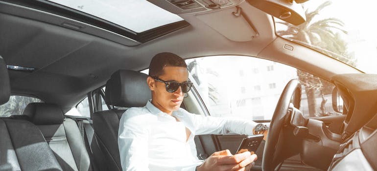 man driving a car and looking at smartphone
