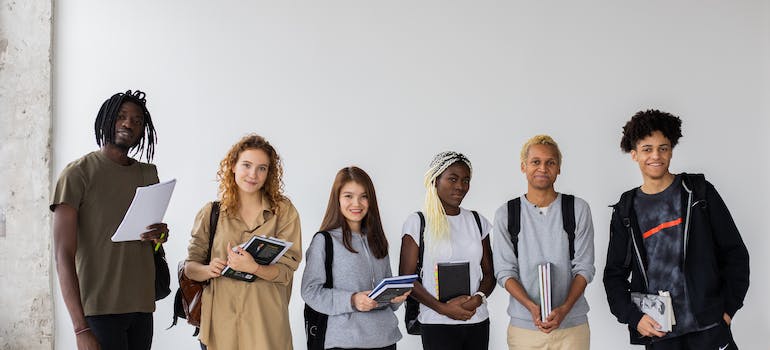 group of multiethnic students standing and holding books in college they got accepted to after moving from Washington to New York