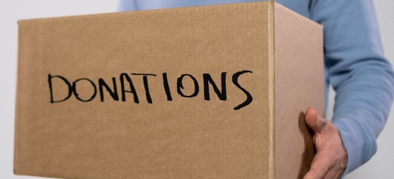 A person holding a box with donations written on it
