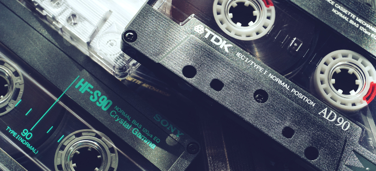 Close-up of audio cassette tapes with prominent labels, featuring detailed text and reel-to-reel design.