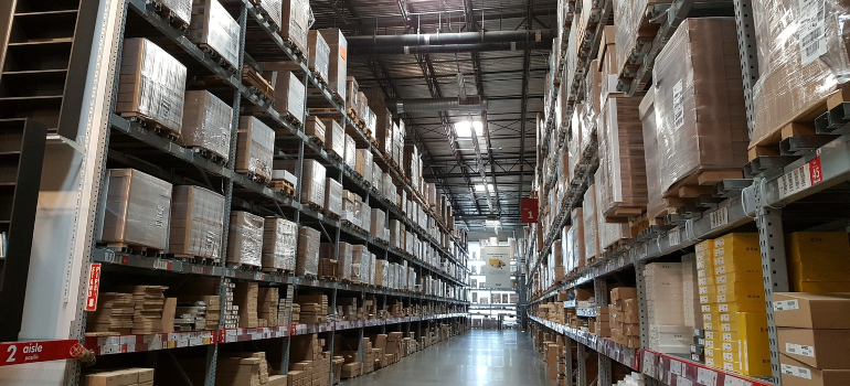 Rows of high shelving units in a spacious warehouse, filled with packaged items.