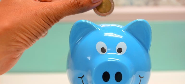 A person putting money inside a blue piggybank
