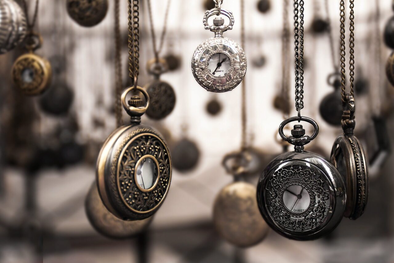 A collection of vintage pocket watches with intricate designs, suspended in mid-air against a blurred background.