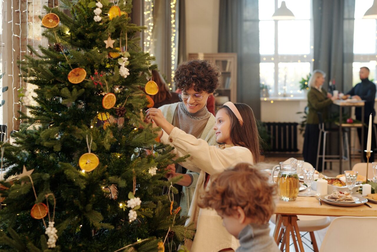 A family decorating the Christmas tree using the ornaments they just unpacked.