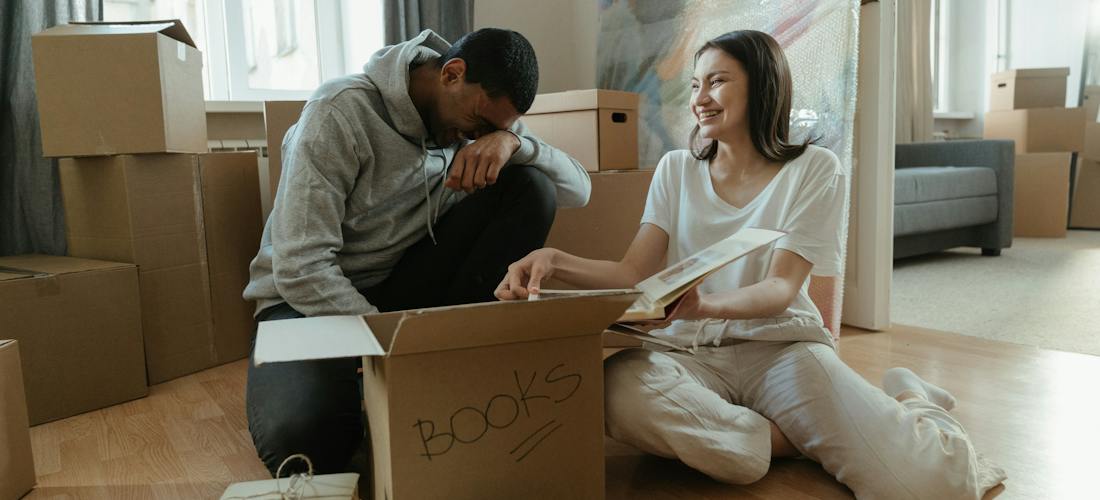 A couple surrounded by moving boxes packing for a move