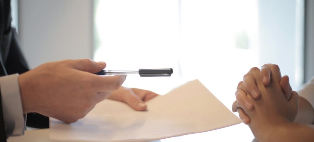 A person giving pen and paper to another person