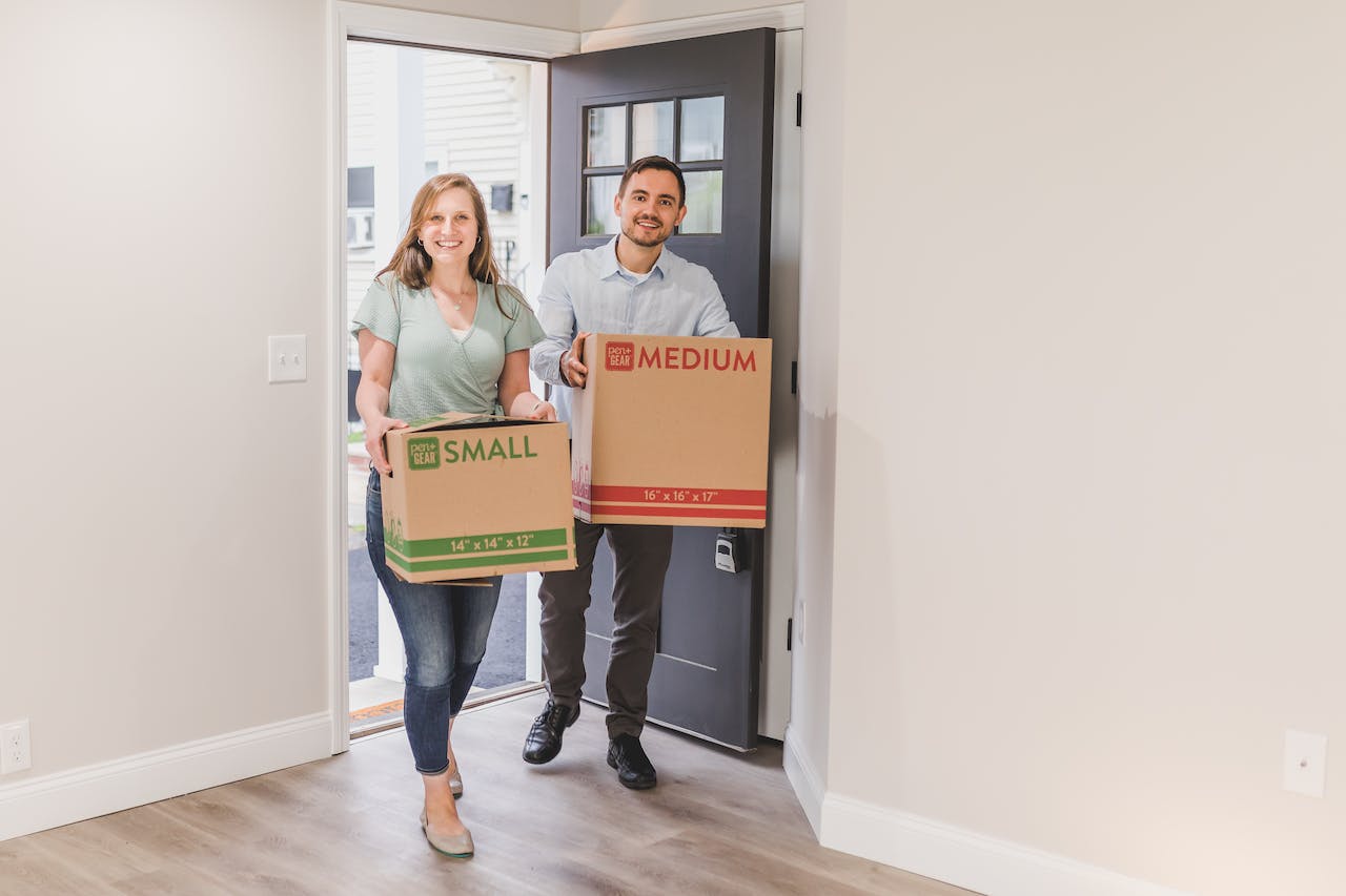 couple at the door carry small and medium sized boxes