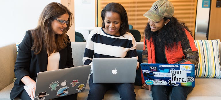 three young women looking at their lap tops