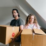 a couple holding boxes and moving from Atlanta to Detroit