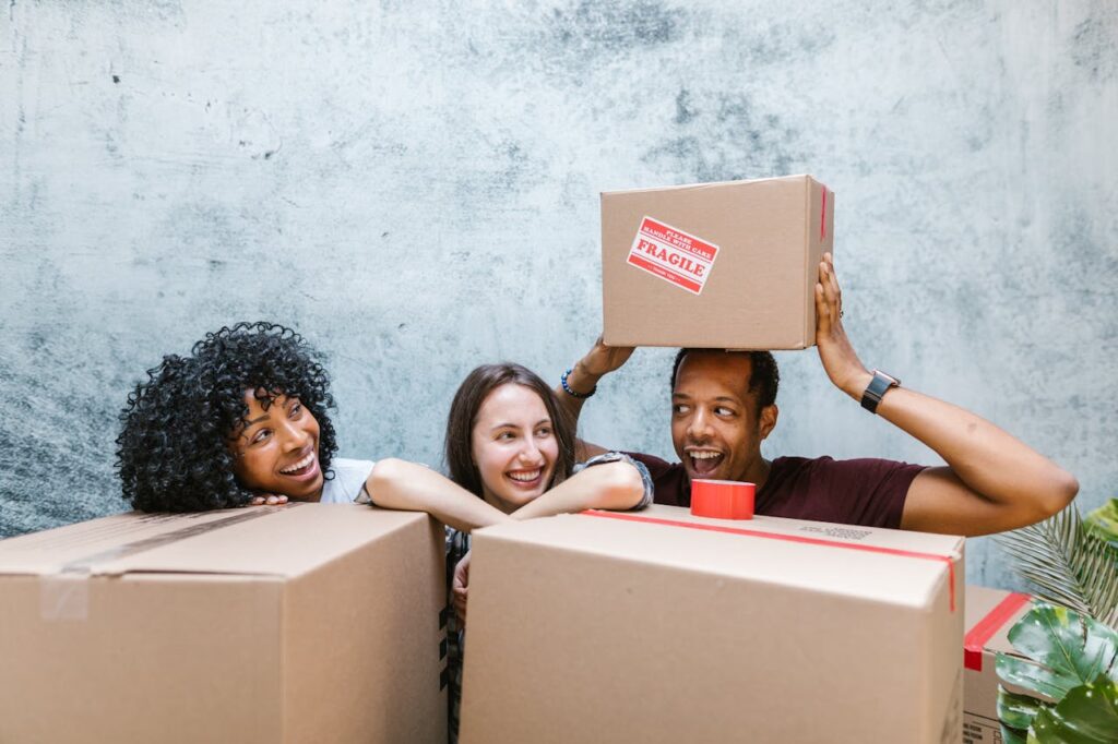three people standing behind boxes and having fun while preparing for moving from California to Florida