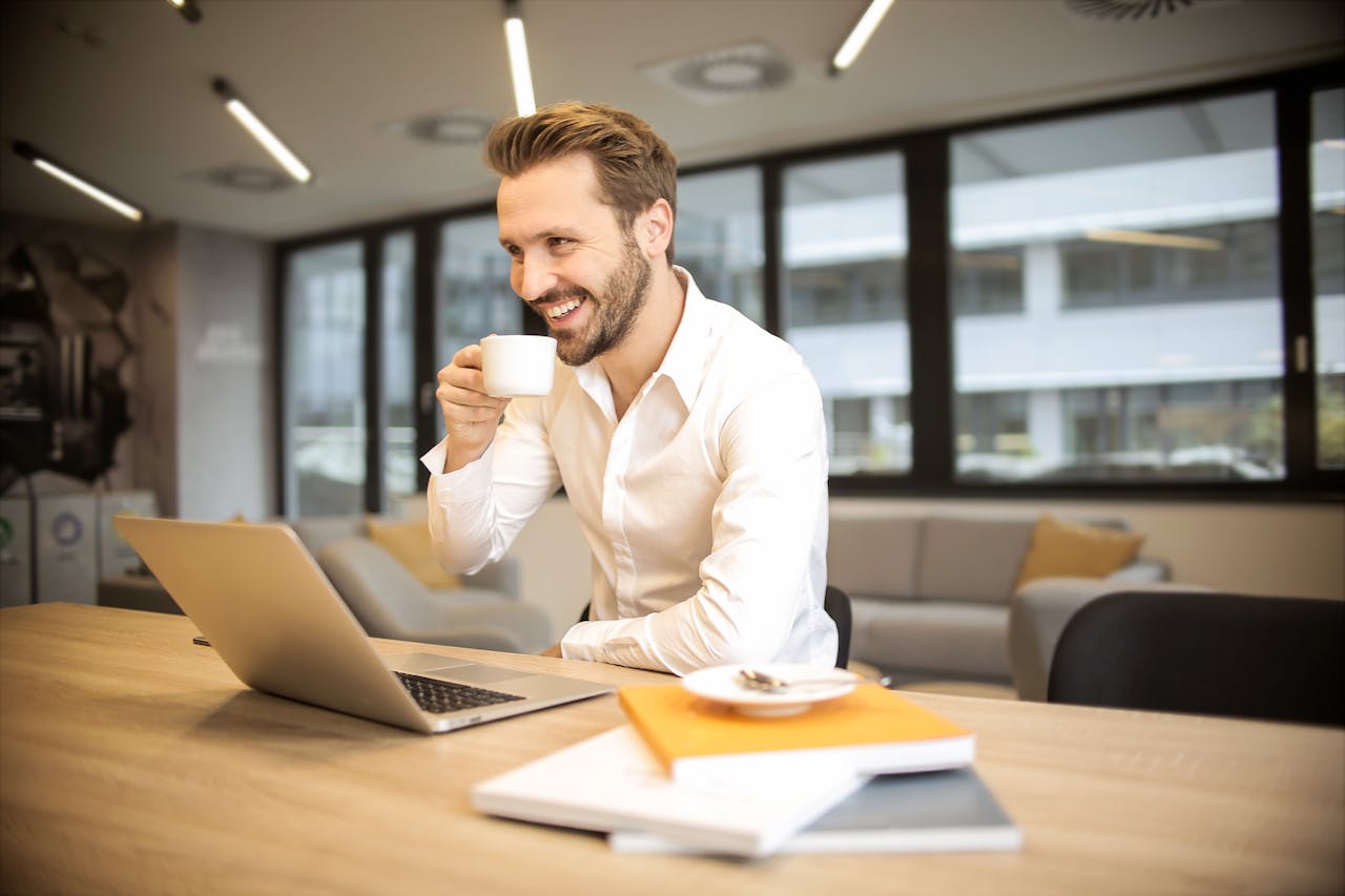 man drinking coffee and smiling after moving to one of the best cities for job seekers in Delaware
