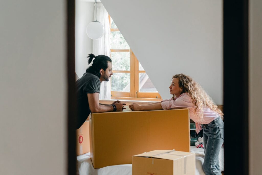man and woman standing with a big box and talking about moving a piano