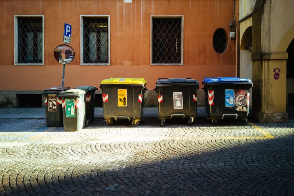 three black dumpsters and trash bins