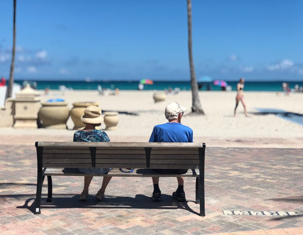 two elderly people sitting at a beach after moving from Minneapolis to Miami
