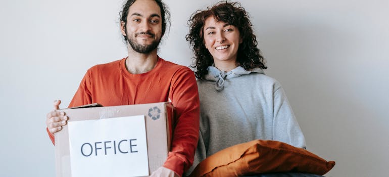 a couple holding a box and a pillow