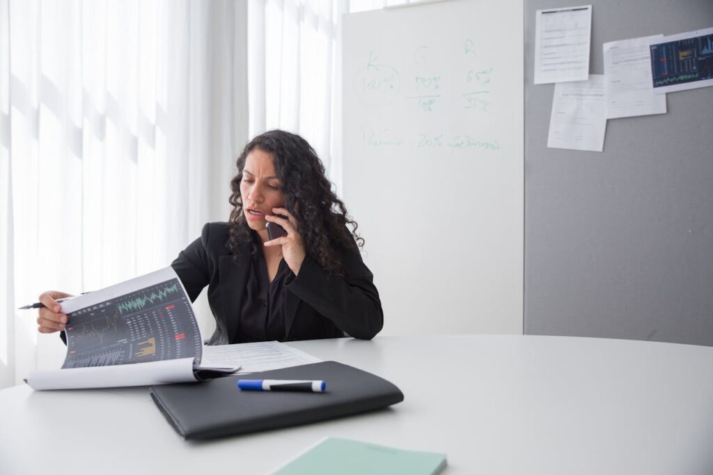 woman looking at some papers and talking on a phone