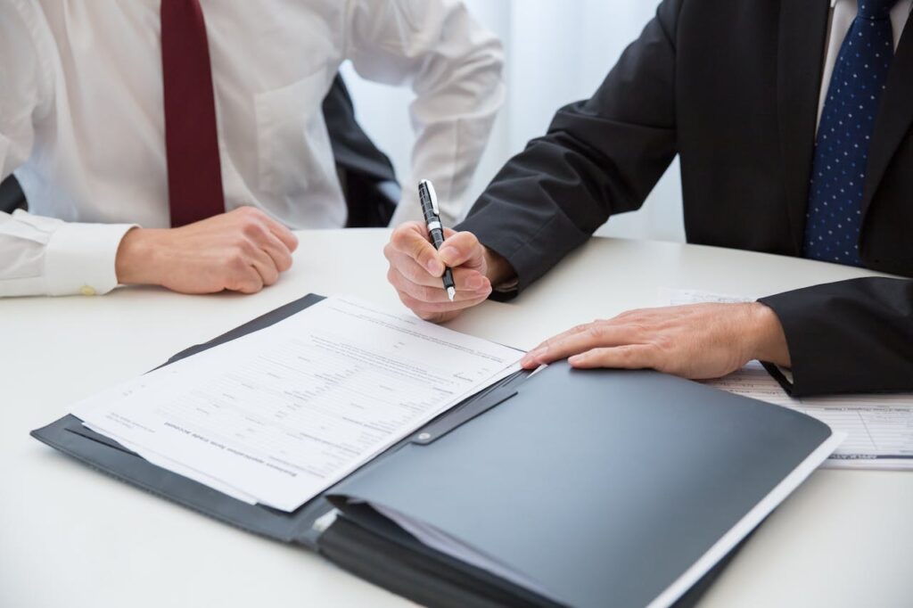 man sitting near another man and signing papers