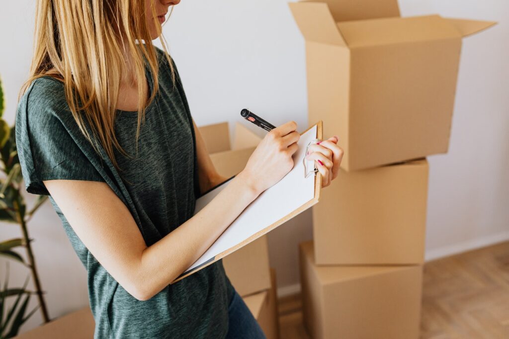 woman writing notes near boxes before moving from Oregon to Arkansas
