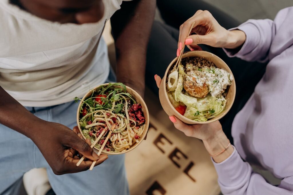 two women holding bowls with food