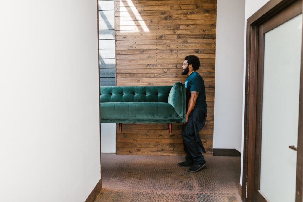 a man carrying a green couch