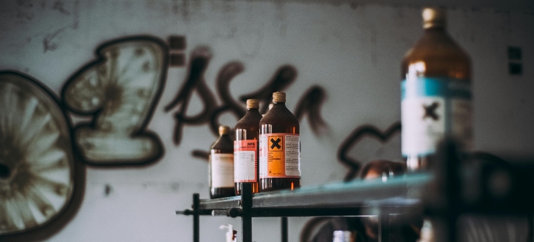 Bottles of hazardous liquids on a shelf in an industrial setting.