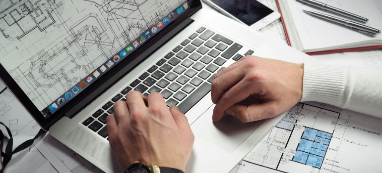 Man Using Turned-on Macbook Pro on White Printer Papers