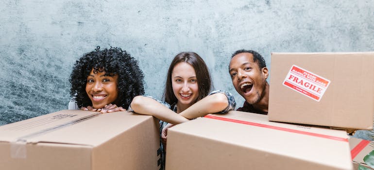 people behind moving boxes smiling before packing and moving electronics