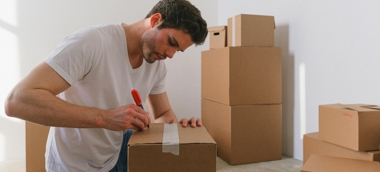 Man labeling a cardboard box while packing.