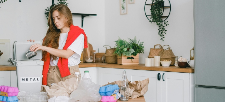 Woman organizing recyclables in a modern kitchen and wondering how do you pack liquids for moving.