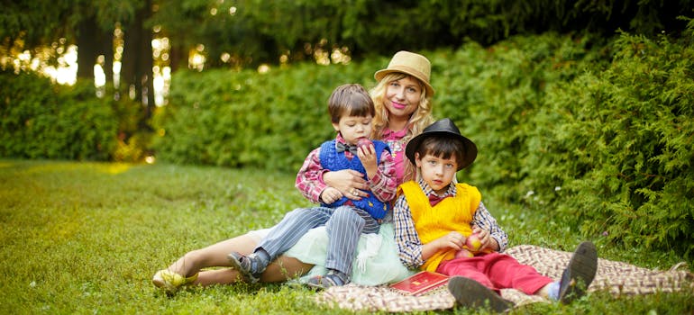 woman and two kids sitting on green grass