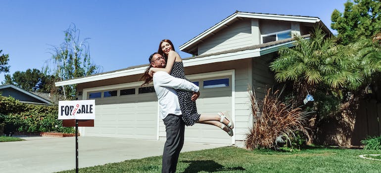 a couple hugging in front of their new home