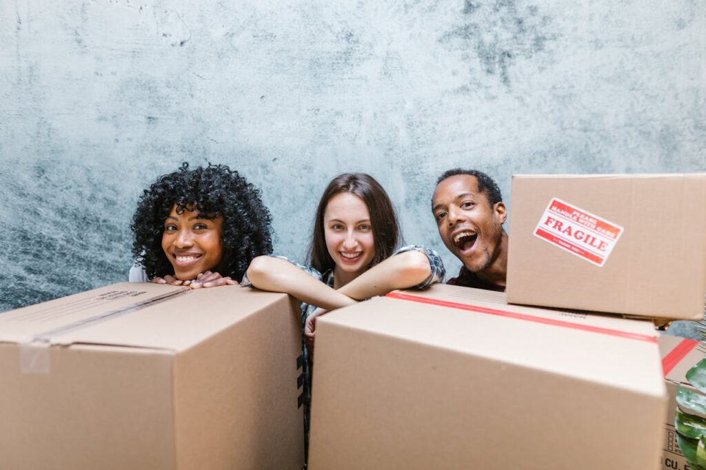 two women and a man having fun behind moving boxes