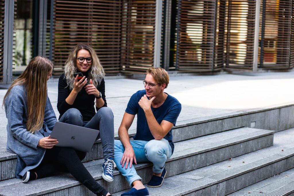 two young women and a man sitting on stairs