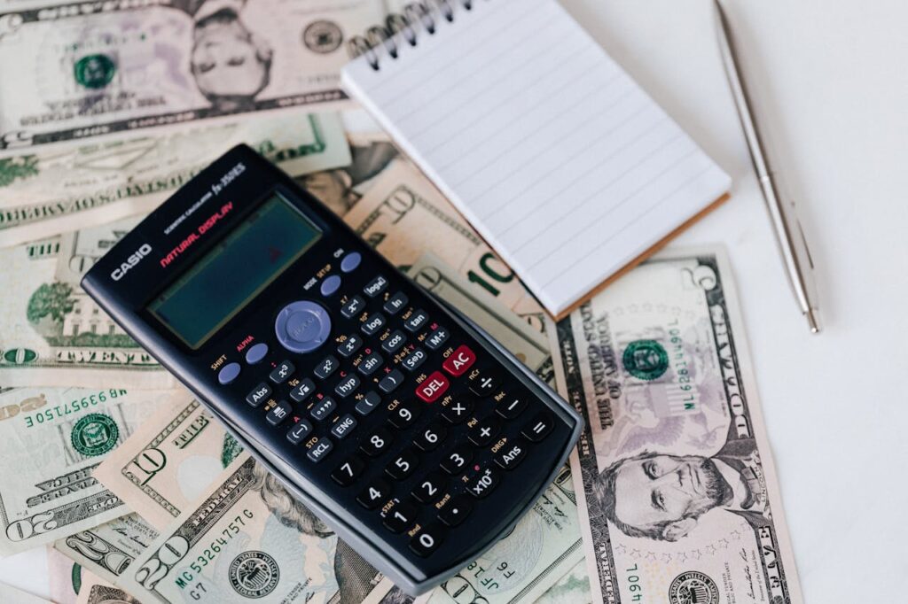calculator, money and notebook on table