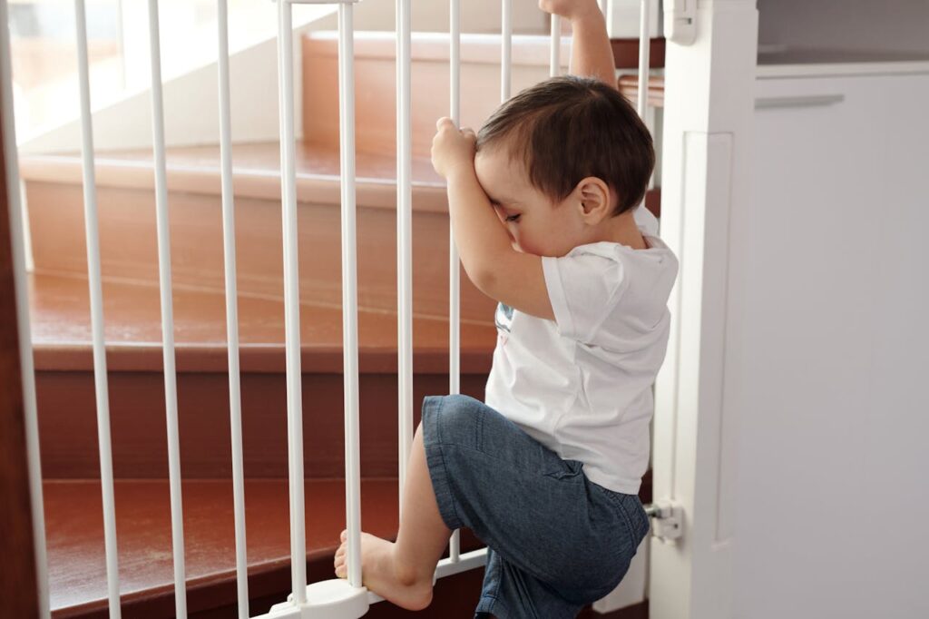 boy trying to climb up a stair gate