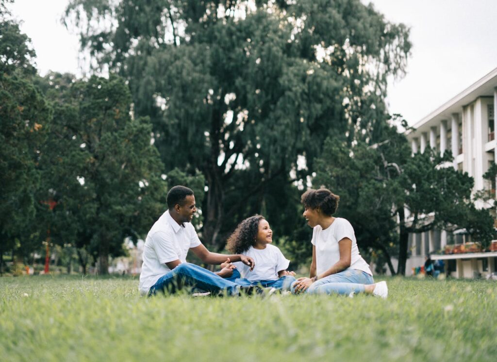 family of three sitting on green grass