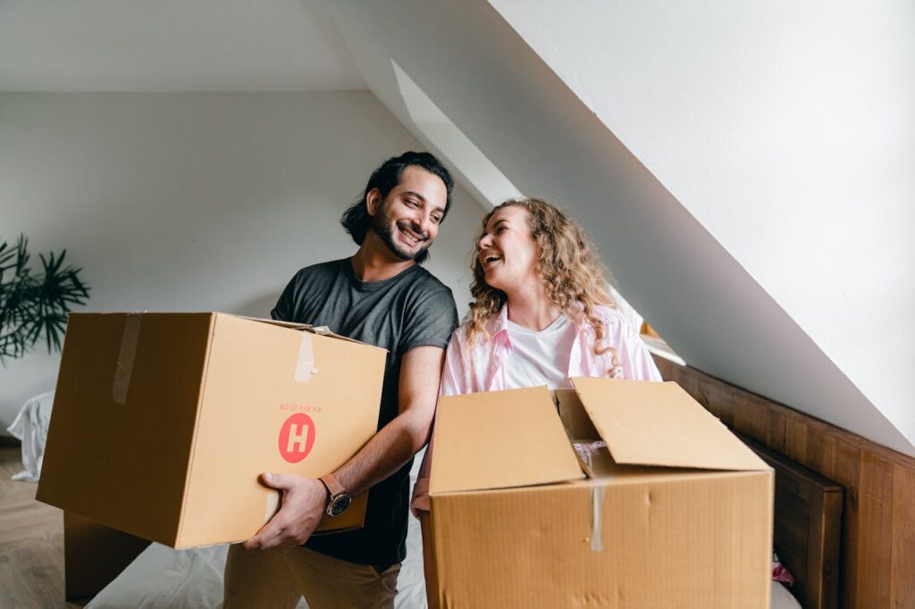 man and woman standing and holding boxes