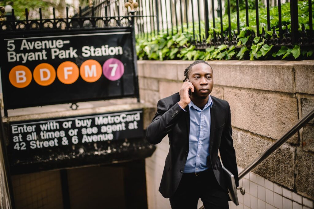 Serious black businessman talking on smartphone while exiting subway
