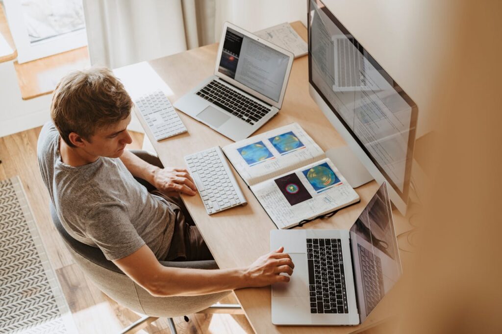 man sitting in front of three computers