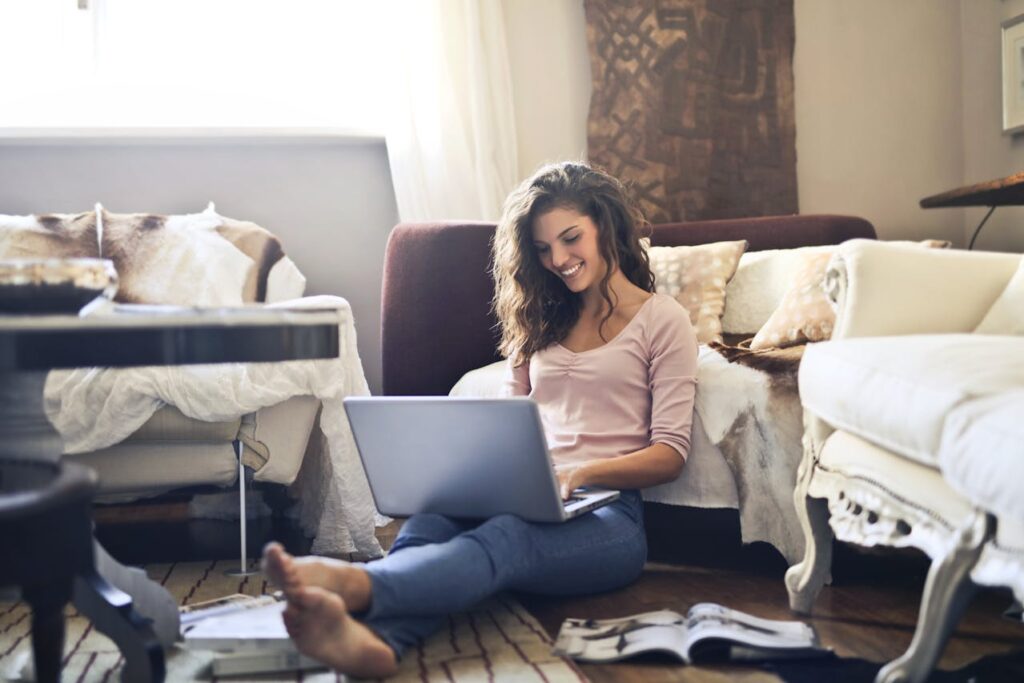 Woman Smiling While Using Laptop and reading about things you must do after moving to NYC